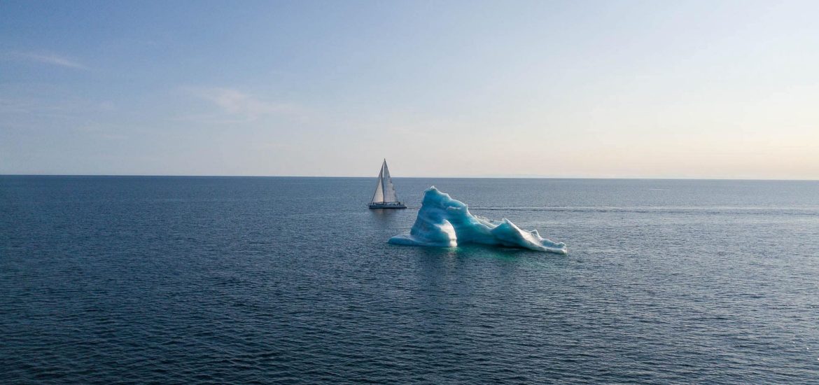 Dogbark sails bye a large iceberg in open water